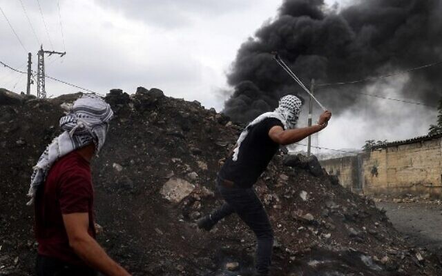 Palestinian demonstrators take cover during clashes with Israeli soldiers following a protest against the expropriation of Palestinian land by Israel in the village of Kfar Qaddum in the West Bank on October 7, 2022. (JAAFAR ASHTIYEH / AFP)