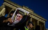 A demonstrator displays a portrait of Iran's supreme leader Ali Khamenei inscribed with the word terrorist during a rally in support of protestors in Iran, in Berlin on October 7, 2022. (John MACDOUGALL / AFP)