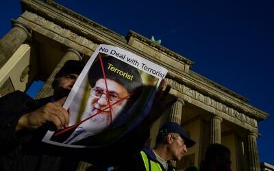 A demonstrator displays a portrait of Iran's supreme leader Ali Khamenei inscribed with the word terrorist during a rally in support of protestors in Iran, in Berlin on October 7, 2022. (John MACDOUGALL / AFP)