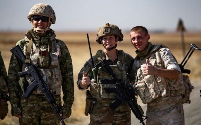 Soldiers of a Russian military convoy and their US counterparts pose for pictures as their patrol routes intersect in an oil field near Syria's al-Qahtaniyah town in the northeastern Hasakah province, close to the border with Turkey, on Octobre 8, 2022. (Delil Souleiman/AFP)