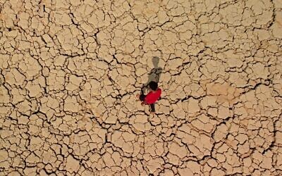 A youth walks on cracked and dried up soil at the Hawizeh marshes, which straddle Iraq's border with Iran, in the southeastern Maysan province on October 8, 2022. (Asaad NIAZI / AFP)