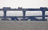 Workers restore the railway tracks on the Kerch bridge that links Crimea to Russia, near Kerch, on October 9, 2022, a day after it was damaged by a blast. (Photo by AFP)