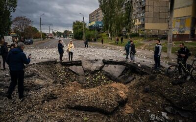 Local residents examine a crater following a missile strike in Dnipro on October 10, 2022, amid Russia's invasion of Ukraine. (Dimitar Dilkoff/AFP)