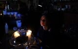 A barista works by candlelight in a cafe without electricity in western Ukrainian city of Lviv, October 11, 2022. (Yuriy Dyachyshyn/AFP)