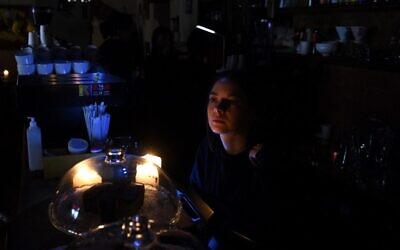 A barista works by candlelight in a cafe without electricity in western Ukrainian city of Lviv, October 11, 2022. (Yuriy Dyachyshyn/AFP)