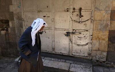 A Palestinian man walks in the Old City of Jerusalem on October 12, 2022, during a general strike by shops in solidarity with Shuafat refugee camp, where Israeli forces have been searching for the suspect in a deadly shooting attack. (Ahmad Gharabli/AFP)