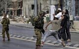 Illustrative: Israeli soldiers stand by as Israeli settlers throw stones at Palestinians during clashes in the town of Huwara in the West Bank on October 13, 2022. (Oren Ziv/AFP)