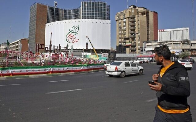 Iranians drive past a huge billboard which reads in Persian, 'The women of my land, Iran,' in Valiasr Square in the capital Tehran, on October 14, 2022.  (AFP)