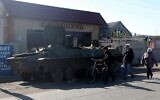 Local residentsv walk past a destroyed Russian personnel armoured carrier in the town of Kupiansk, Kharkiv region, on October 17, 2022, amid the Russian military invasion of Ukraine. (Anatolii Stepanov / AFP)