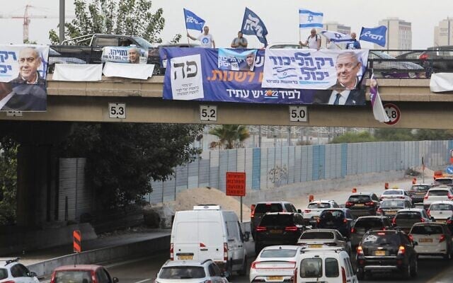 Likud supporters wave party and national flags on an overpass overlooking a highway in the coastal city of Tel Aviv, on October 23, 2022. (GIL COHEN-MAGEN / AFP) Likud supporters wave party and national flags on an overpass overlooking a highway in the coastal city of Tel Aviv, on October 23, 2022. (GIL COHEN-MAGEN / AFP)
