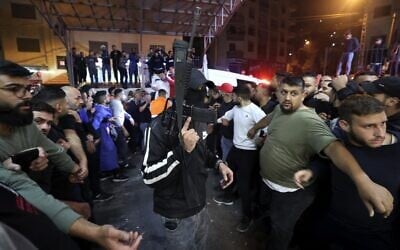 A member of the Lion's Den group escorts injured men into a hospital after clashes with Israeli forces in Nablus, in the West Bank on early October 25, 2022. (Jaafar Ashtiyeh/AFP)
