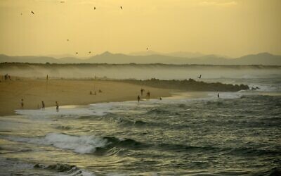 People walk along the beach in warm weather, in Capbreton, southwestern France, on October 27, 2022. (GAIZKA IROZ / AFP)