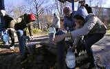 Kyiv residents fill plastic containers and bottles at a water pump in one of the parks in the Ukrainian capital Kyiv on October 31, 2022 (SERGEI CHUZAVKOV / AFP)