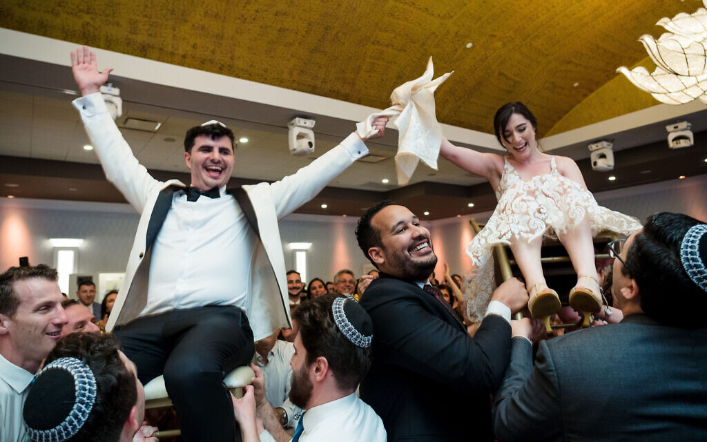 Alex Zeldin and Tamar Caplan are lifted on chairs during their wedding reception, August 21, 2022. (JC Lemon Photography/ via JTA) Alex Zeldin and Tamar Caplan are lifted on chairs during their wedding reception, August 21, 2022. (JC Lemon Photography/ via JTA)