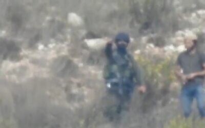 Dudu Assayag (left) the security coordinator for the Har Bracha settlement is seen pointing at a group of Palestinians, as the settler next to him prepares to hurl a tear gas grenade, October 21, 2022. (Screenshot: Yesh Din)