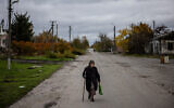 An elderly woman walks down a street to get her pension from a Ukraine post office car in the village of Drobysheve in eastern Ukraine's Donetsk region, on October 28, 2022. (Dimitar Dilkoff/AFP)