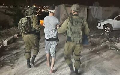 In this handout photo, IDF troops detain the Palestinian suspected of stabbing an Israeli man in the West Bank village of al-Funduq on October 25, 2022. (Israel Defense Forces) In this handout photo, IDF troops detain the Palestinian suspected of stabbing an Israeli man in the West Bank village of al-Funduq on October 25, 2022. (Israel Defense Forces)