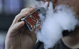Illustrative. A man using an electronic cigarette exhales in Mayfield Heights, Ohio, on October 4, 2019. (AP Photo/ Tony Dejak, File)