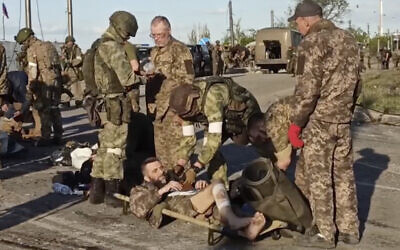 In this photo taken from video released by the Russian Defense Ministry Press Service, Russian servicemen frisk Ukrainian servicemen as they are being evacuated from the besieged Azovstal steel plant in Mariupol, Ukraine, May 17, 2022. (Russian Defense Ministry Press Service via AP)