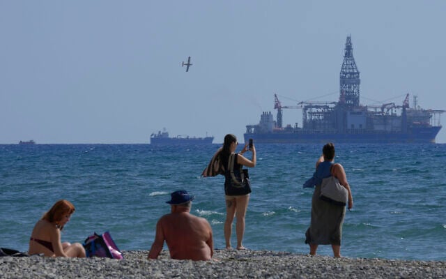 Illustrative: People on the beach take photos of the 'Tungsten Explored' drilling ship, in the southern coastal city of Larnaca, Cyprus, November 3, 2021. (AP Photo/Petros Karadjias, File) Illustrative: People on the beach take photos of the 'Tungsten Explored' drilling ship, in the southern coastal city of Larnaca, Cyprus, November 3, 2021. (AP Photo/Petros Karadjias, File)