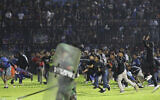 Soccer fans enter the pitch during a clash between supporters at Kanjuruhan Stadium in Malang, East Java, Indonesia, Saturday, Oct. 1, 2022. Panic following police actions left over 100 dead, mostly trampled to death, police said Sunday. (AP/Yudha Prabowo)