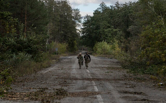 Ukrainian servicemen walk along road while they search for dead bodies of their comrades in recently recaptured town of Lyman, Ukraine, October 3, 2022. (AP Photo/Evgeniy Maloletka) Ukrainian servicemen walk along road while they search for dead bodies of their comrades in recently recaptured town of Lyman, Ukraine, October 3, 2022. (AP Photo/Evgeniy Maloletka)