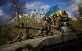 Ukrainian soldiers sit on an armored vehicle as they drive on a road between Izium and Lyman, recently retaken areas in Ukraine, on October 4, 2022. (AP Photo/Francisco Seco)