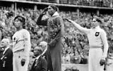 America's Jesse Owens, center, salutes during the presentation of his gold medal for the long jump, alongside silver medalist Luz Long, right, of Germany, and bronze medalist Naoto Tajima, of Japan, during the 1936 Summer Olympics in Berlin, August 11, 1936  (AP Photo/File)