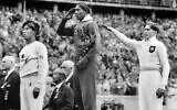 The United States' Jesse Owens, center, salutes during the presentation of his gold medal for the long jump, alongside German silver medalist Luz Long, who performs a Nazi salute, right, and bronze medalist Naoto Tajima, of Japan, during the eleventh Summer Olympics in Berlin, Germany, August 11, 1936. (AP Photo)