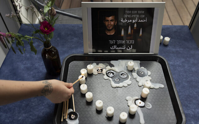 A volunteer lights a candle during a vigil for Ahmad Abu Murkhiyeh, at an LGBTQ shelter in Tel Aviv, Israel, Oct. 7, 2022. Hebrew and Arabic reads "we will remember you forever". (AP/Oded Balilty)