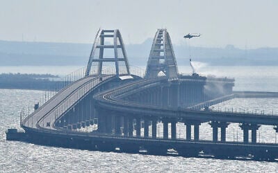A helicopter drops water to stop fire on Crimean Bridge connecting Russian mainland and Crimean peninsula over the Kerch Strait, in Kerch, October 8, 2022. (AP Photo)