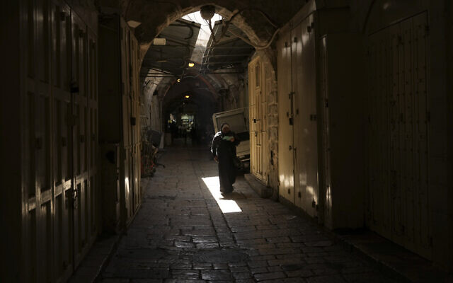 A woman walks past shuttered shops in Jerusalem's Old City on October 12, 2022. (AP Photo/Mahmoud Illean) A woman walks past shuttered shops in Jerusalem's Old City on October 12, 2022. (AP Photo/Mahmoud Illean)