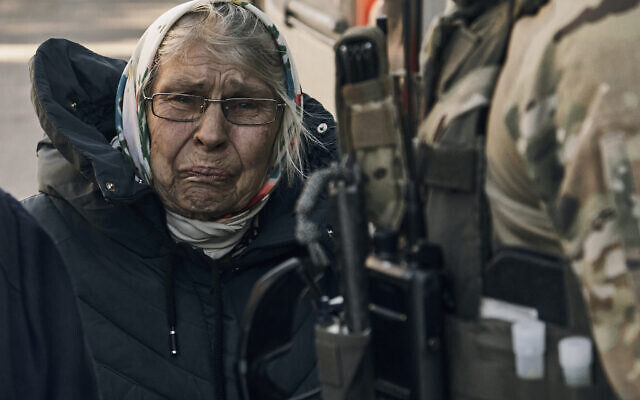 An elderly woman reacts as she leaves her house located in a combat zone in the village of Zarechne, Donetsk region, Monday, Oct. 17, 2022. (AP Photo/LIBKOS)