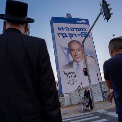 People walk past an election campaign billboard showing Benjamin Netanyahu, former Israeli prime minister and the head of the Likud party, in Bnei Brak, an ultra-Orthodox Tel Aviv suburb, Oct. 25, 2022. The Hebrew on the billboard reads: "The 61st seat depends only on you." (AP Photo/Oded Balilty)