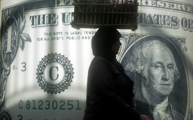FILE - An Egyptian vendor walks past a poster showing a U.S. dollar outside an exchange office in Cairo, Egypt, Wednesday, Nov. 9, 2016. (AP Photo/Amr Nabil, File) FILE - An Egyptian vendor walks past a poster showing a U.S. dollar outside an exchange office in Cairo, Egypt, Wednesday, Nov. 9, 2016. (AP Photo/Amr Nabil, File)