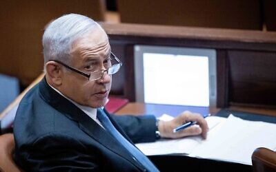 Opposition leader Benjamin Netanyahu, pen in hand, at his Knesset seat during a plenum session on October 11, 2021. (Yonatan Sindel/Flash90)