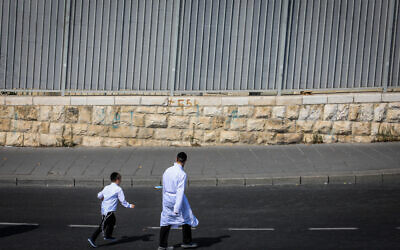People walk on the empty road at the entrance to Jerusalem, on Yom Kippur, the Day of Atonement, October 5, 2022. (Jamal Awad/Flash90)