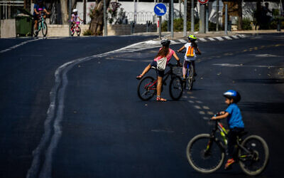 People ride their bicycles and walk along the empty road in Jerusalem, on Yom Kippur, the Day of Atonement, and the holiest of Jewish holidays, October 4, 2022. Photo by Yonatan Sindel/Flash90 *** Local Caption *** יום כיפור
כיפורים
רחוב ריק
רחובות ריקים
אופניים
ירושלים
כביש
ערב
