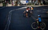 People ride their bicycles and walk along the empty road in Jerusalem, on Yom Kippur, the Day of Atonement, and the holiest of Jewish holidays, October 4, 2022. (Yonatan Sindel/Flash90)