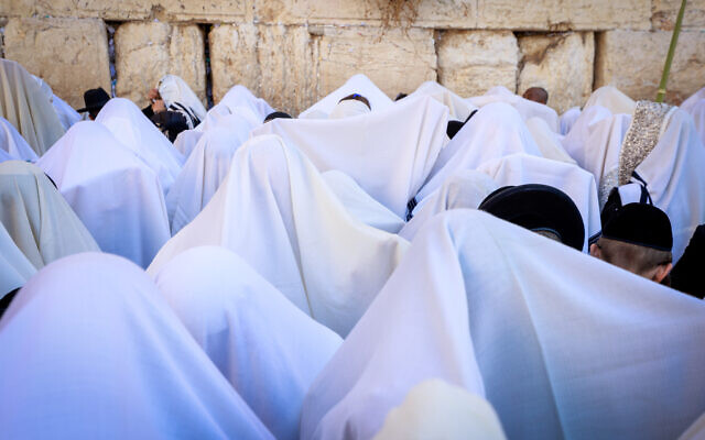 Jewish worshippers cover themselves with prayer shawls as they pray at the Western Wall in Jerusalem's Old City during the priestly blessing at the Jewish holiday of Sukkot, October 12, 2022. (Olivier Fitoussi/Flash90)