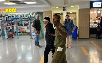 An Israeli soldier escorts a blindfolded and handcuffed Palestinian teenager through the Shaare Zedek hospital in Jerusalem, October 24, 2022. (Courtesy; Used in accordance with Clause 27a of the Copyright Law)