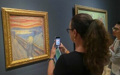 File: Picture taken on August 3, 2022 shows a visitor taking pictures of Edvard Munch's iconic painting "The Scream" at the National Museum in Oslo, Norway.(Heiko Junge / NTB / AFP)