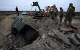 Ukrainian soldiers pull a car out of a crater on the road in Kherson region on November 13, 2022, amid Russia's invasion of Ukraine. (AFP)