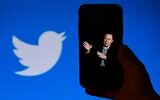 A phone screen displays a photo of Elon Musk with the Twitter logo shown in the background, in Washington, DC, October 4, 2022. (Olivier Douliery/AFP)
