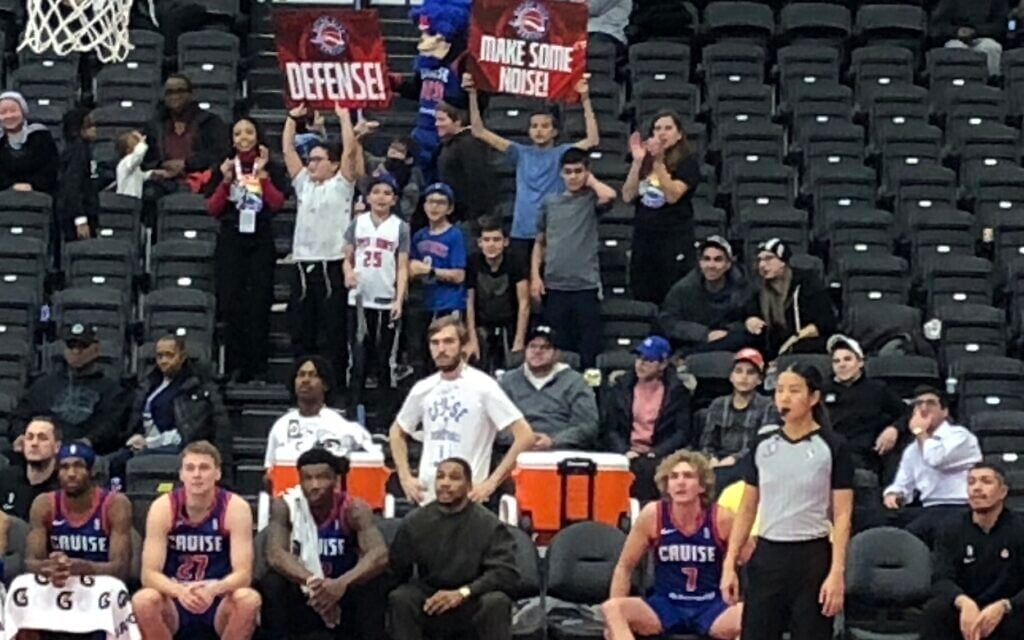 Motor City Cruise player Ryan Turell (front-right) watches his team from the bench as his Orthodox fans cheer on the NBA G League team from the stands in Detroit, November 17, 2022. (Andrew Lapin/JTA)