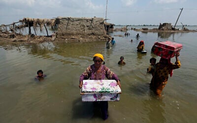 Women carry belongings salvaged from their flooded home after monsoon rains, in the Qambar Shahdadkot district of Sindh Province, Pakistan, September 6, 2022. (AP Photo/Fareed Khan, File)