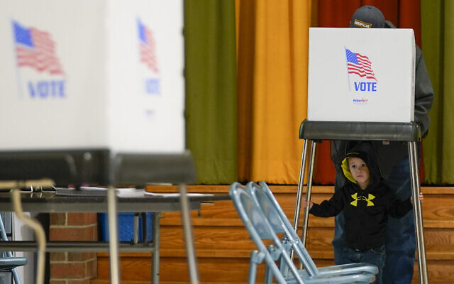 Jacob Lewis, 3, waits at a privacy booth as his grandfather, Robert Schroyer, fills out his ballot while voting at Sabillasville Elementary School, November 8, 2022, in Sabillasville, Maryland. (AP Photo/Julio Cortez)