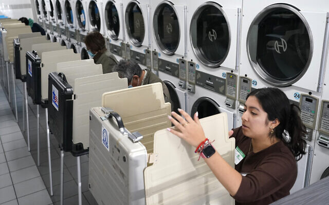 US poll worker Alany Gonzalez sets up another voting booth in front of dryers at the Su Nueva Lavanderia near Chicago's Midway Airport, November 8, 2022, in Chicago. (AP Photo/Charles Rex Arbogast)