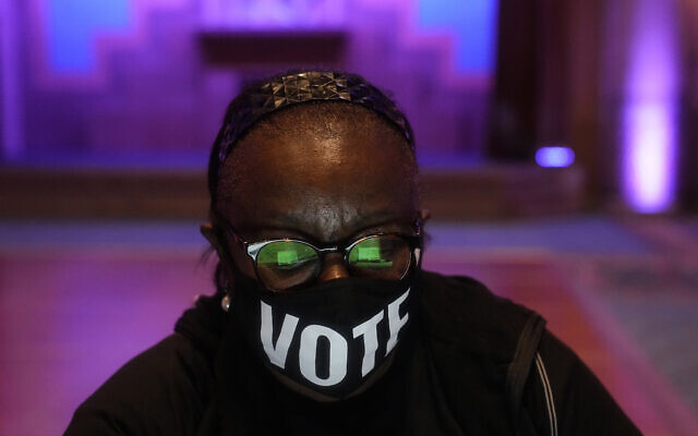 A poll worker wears a "vote" mask as they check in voters on US Election Day, November 8, 2022, in Atlanta. (AP Photo/Brynn Anderson)