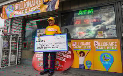 Business owner Joe Chahayed holds a check outside Joe's Service Center in Altadena, northeast of Los Angeles Nov. 8, 2022. For selling the winning ticket, (AP Photo/Damian Dovarganes)